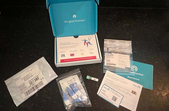 The LetsGetChecked Diabetes Test Kit on a table, including four lancets, a small sample collection vial, paper instructions and the return shipping bag.